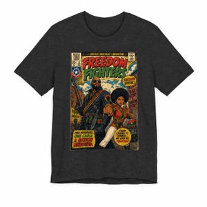 May include: A charcoal gray short-sleeve t-shirt featuring a comic book cover graphic titled Freedom Fighters. The artwork depicts two figures in a city setting with text including Juneteenth Special, Black History Is American History, and Two Warriors. One Cause. A Nation Unbound.