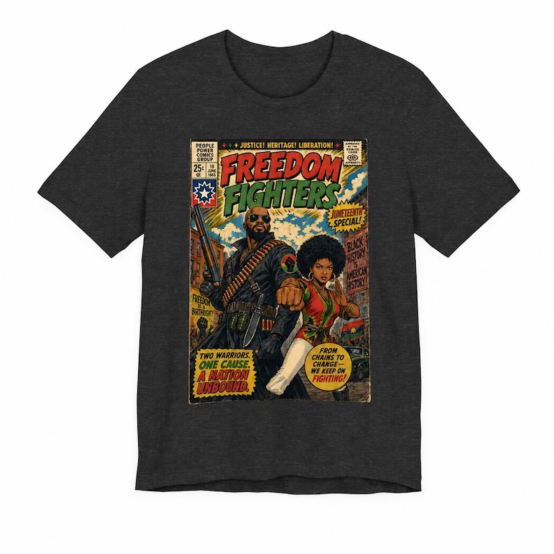 May include: A charcoal gray short-sleeve t-shirt featuring a comic book cover graphic titled Freedom Fighters. The artwork depicts two figures in a city setting with text including Juneteenth Special, Black History Is American History, and Two Warriors. One Cause. A Nation Unbound.