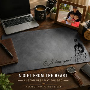 May include: A rectangular dark gray desk mat featuring a custom laser-engraved illustration of a person with two children on the right side and the cursive text "We love you!" printed in the lower center area of the smooth surface.