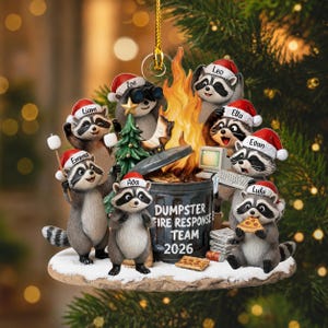 May include: A decorative Christmas ornament featuring seven raccoons wearing Santa hats around a dumpster fire. The dumpster is labeled DUMPSTER FIRE RESPONSE TEAM 2026. The raccoons are named Emma, Liam, Zoe, Leo, Ella, Evan, and Luke.