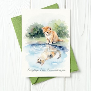 May include: Watercolor greeting card featuring an orange tabby kitten sitting by a pond, with its reflection in the water. The card is inside a green envelope. Text reads: "Everything I am, I am because of you."