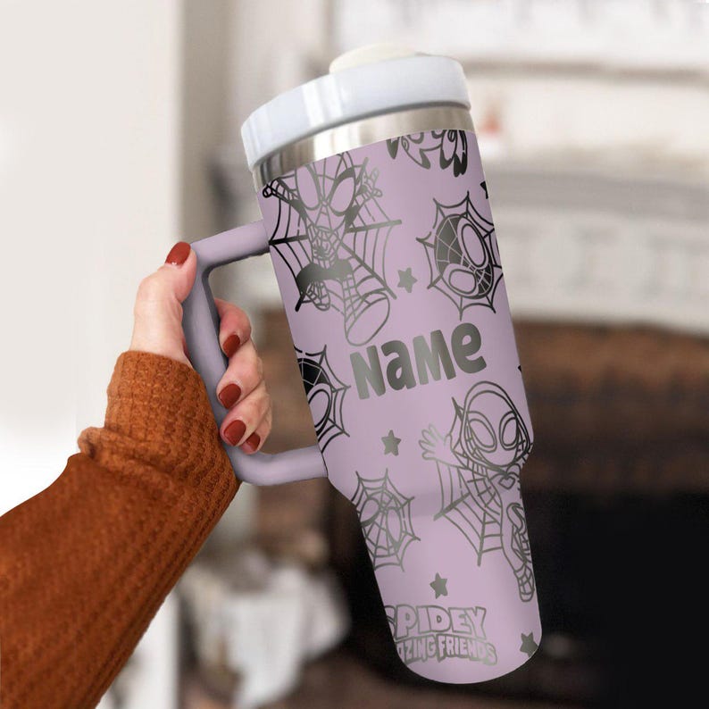 Puede incluir: Un vaso de color lavanda con asa, con dise&ntilde;os de Spidey y telara&ntilde;as. El vaso tiene la palabra "Name" impresa, junto con el texto "Spidey Amazing Friends".