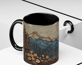 May include: A black-handled coffee mug with a mountain and forest scene. The mug displays a detailed illustration of a mountain range, trees, and flowers in shades of blue, brown, and gold. The interior of the mug is black.