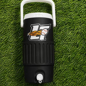 May include: Black and white insulated water cooler with a white handle. The cooler features a baseball logo with a baseball and flames. The cooler has a white spigot and is on a green surface.