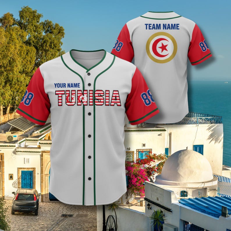 K&ouml;nnte beinhalten: Wei&szlig;es Baseball-Trikot mit roten &Auml;rmeln und gr&uuml;nen Zierleisten. Das Trikot zeigt das Wort "TUNISIA" in Rot und Wei&szlig;, mit der Nummer "88" auf den &Auml;rmeln. Auf der R&uuml;ckseite des Trikots befindet sich ein kreisf&ouml;rmiges Emblem mit einem roten Stern.