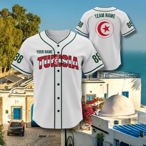 K&ouml;nnte beinhalten: Wei&szlig;es Baseball-Trikot mit gr&uuml;nen Zierleisten und dem Wort "TUNISIA" in roten Buchstaben. Das Trikot hat die Nummer "88" auf den &Auml;rmeln und eine Knopfleiste. Auf der R&uuml;ckseite des Trikots befindet sich ein rotes Stern- und Halbmond-Design.