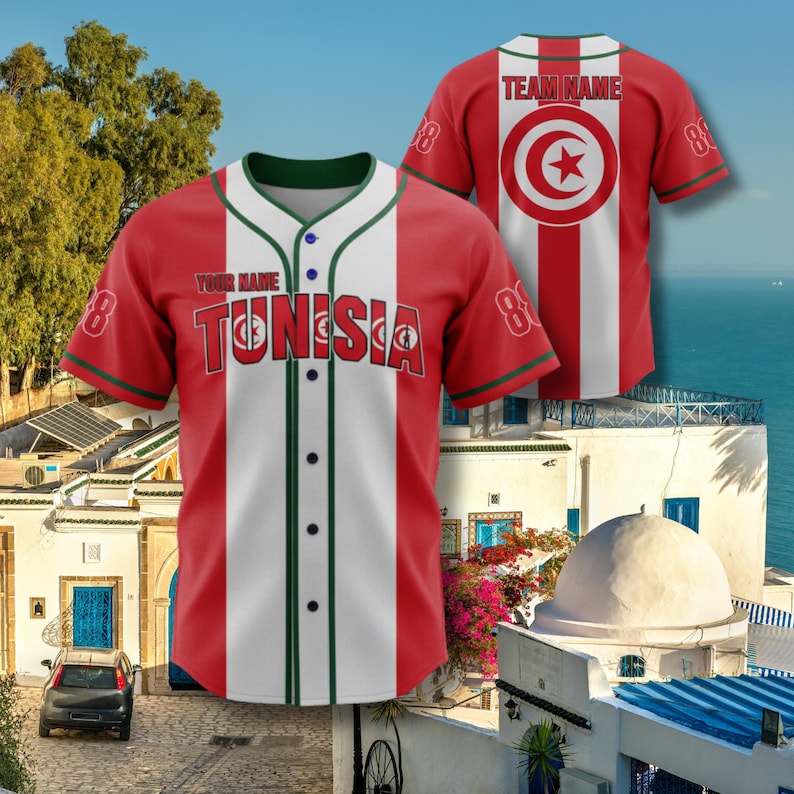 K&ouml;nnte beinhalten: Rotes und wei&szlig;es Baseball-Trikot mit dem Wort "TUNISIA" auf der Brust. Das Trikot hat gr&uuml;ne Verzierungen und die Nummer 8 auf den &Auml;rmeln. Die R&uuml;ckseite des Trikots ist rot mit einem wei&szlig;en Streifen und einem kreisf&ouml;rmigen Emblem mit einem Stern.