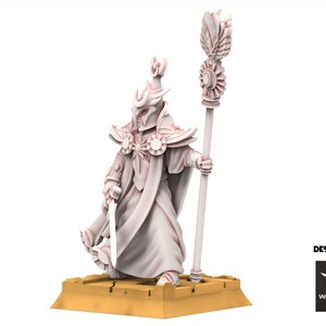 Op de afbeelding: Een lichtgekleurd fantasiefiguur van een geklede figuur met een staf en een zwaard. Het figuur heeft een helm en sierlijke schoudervullingen. Het beeldje staat op een goudkleurige basis. De woorden "DESIGNED BY" en het White Angel-logo zijn zichtbaar.
