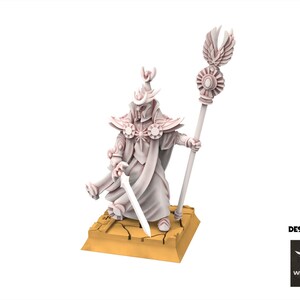 Op de afbeelding: Lichtgekleurd beeldje van een geklede figuur met een zwaard en staf. De figuur staat op een vierkante basis met een gebarsten patroon. De staf heeft een decoratieve top met vleugels. De woorden "DESIGNED BY" en een logo zijn zichtbaar.