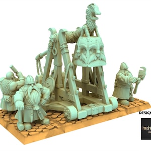 Puede incluir: Un modelo en miniatura de un arma de asedio, un trabuquete, con varias figuras de enanos. El trabuquete es de color verde claro y tiene un diseño detallado. Los enanos también son de color verde claro y posan como si estuvieran trabajando en el arma. La base es de color marrón claro.