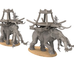 Puede incluir: Dos figuras de elefantes grises con estructuras de madera sobre sus espaldas. Cada elefante tiene múltiples colmillos y está adornado con elementos decorativos. Las figuras se alzan sobre una base beige, sugiriendo un tema de elefante de guerra en miniatura.