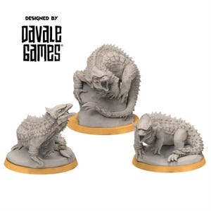May include: Three gray fantasy creature figurines with spiky backs and open mouths. The figurines are on round, gold-colored bases. The text "DESIGNED BY DAVALE GAMES" is printed in black above the figurines.