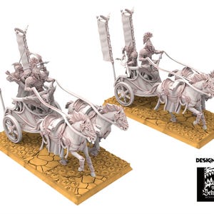 May include: Two miniature white chariots pulled by pairs of horses. Each chariot has two riders and is adorned with decorative elements and banners. The bases are tan with a cracked earth texture. The design is by The Beholder Miniatures.