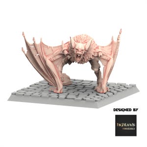 Puede incluir: Una detallada figura de murciélago rosa claro con alas extendidas y boca abierta, de pie sobre una base de adoquines grises. El murciélago tiene un pecho peludo y dientes afilados. La base es rectangular. Se ve el texto "DESIGNED BY" y un logotipo.