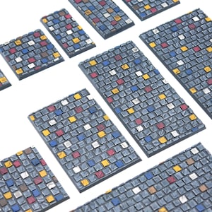 Peut inclure: Une collection de tuiles de terrain miniatures rectangulaires et carrées présentant un motif de pavés gris texturés. Chaque tuile est détaillée avec des pierres individuelles peintes en accents alternés de jaune, rouge, bleu et argent métallique.