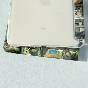May include: A clear iPad case with a colorful design featuring cartoon characters. The case is made of a transparent material, allowing the device's back to be visible. The design includes various illustrations.