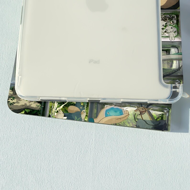 May include: A clear iPad case with a colorful design featuring cartoon characters. The case is made of a transparent material, allowing the device's back to be visible. The design includes various illustrations.