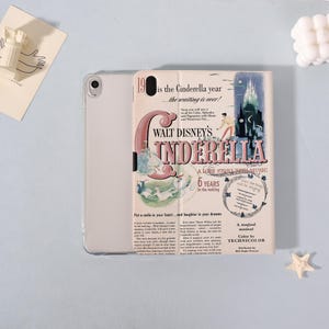 May include: A light-colored tablet case featuring a vintage-style illustration from Walt Disney's Cinderella. The case has a cream-colored background with text and images, including the words "Walt Disney's Cinderella" and "A Love Story with Music."