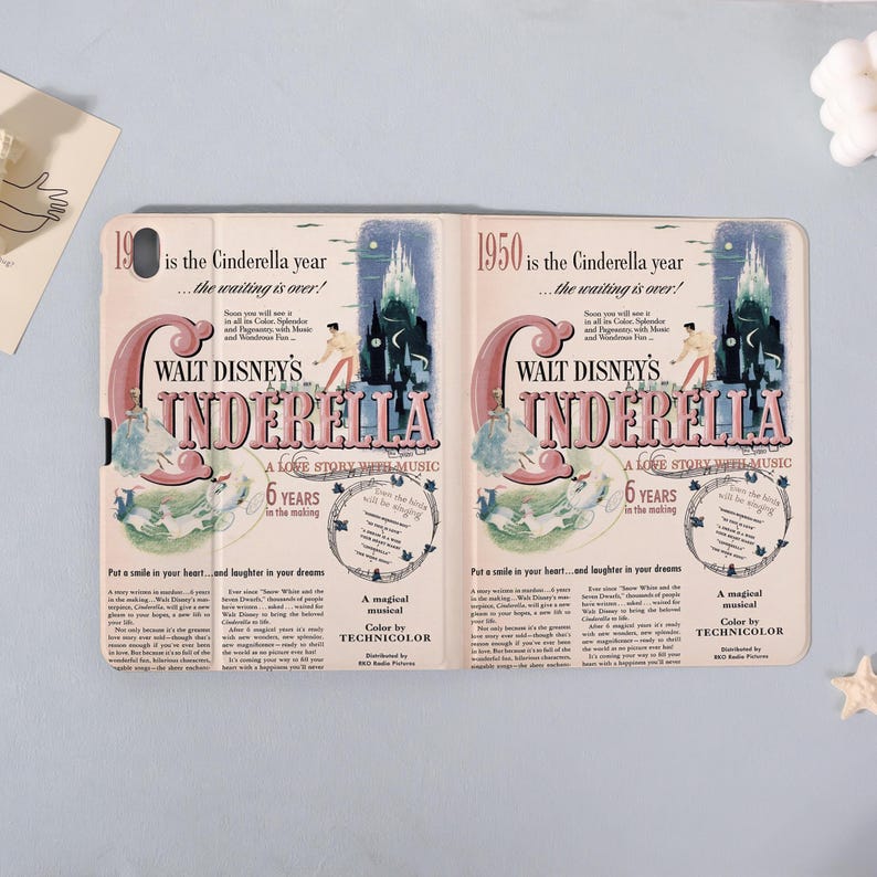 May include: A tablet case featuring a vintage-style design for Walt Disney's Cinderella. The cover displays the movie title, a castle illustration, and text that reads "A Love Story With Music." The case is in a light beige color.