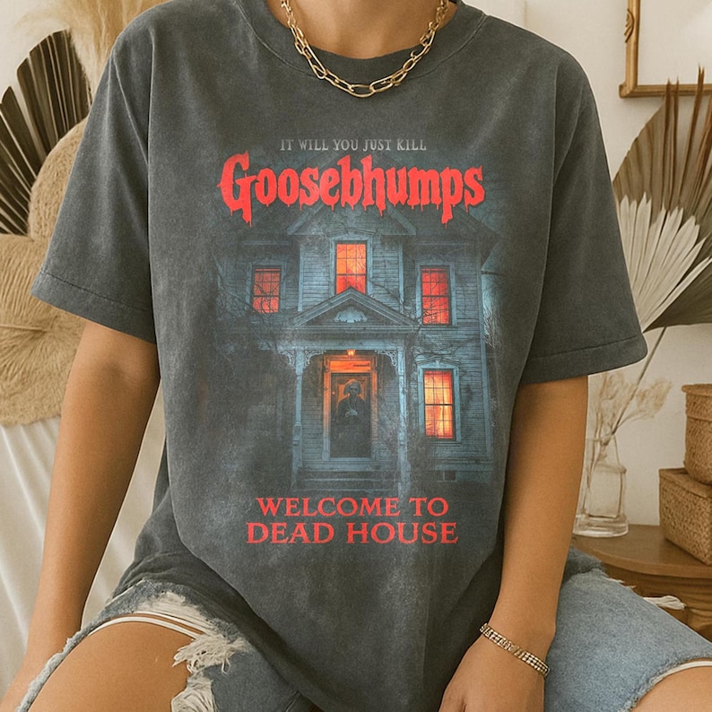 May include: Dark grey t-shirt with the red text "Goosebumps" and a haunted house illustration. The shirt also features the phrases "It Will You Just Kill" and "Welcome to Dead House."