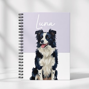 May include: A spiral-bound notebook with a painted portrait of a black and white Border Collie dog. The dog has its tongue out. The name "Luna" is written in cursive above the dog. The background is divided into lavender and white sections.