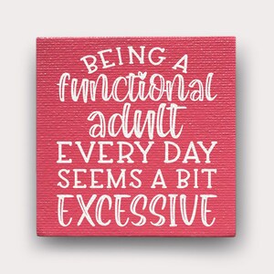 May include: Red canvas sign with white text that reads "Being a functional adult every day seems a bit excessive."