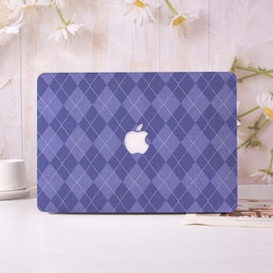 May include: A purple laptop cover with a diamond pattern and a white Apple logo. The cover is a solid color with a repeating pattern of dark and light purple diamonds, and a white Apple logo in the center.