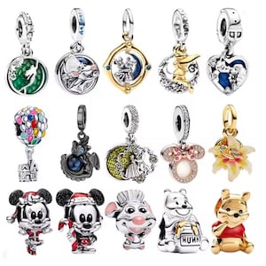 May include: A collection of silver charms with various designs, including Disney characters like Mickey and Minnie Mouse, Winnie the Pooh, and other whimsical elements. Some charms feature colorful accents and gemstones, perfect for bracelets or necklaces.