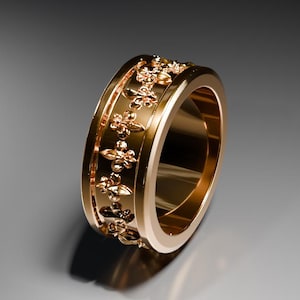 Puede incluir: Un anillo de oro con un diseño detallado de patrones repetidos alrededor de la banda.