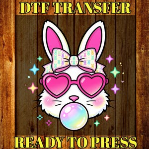 May include: DTF TRANSFER and READY TO PRESS text on a wooden background. A white bunny with pink heart-shaped sunglasses, a bow, and a bubblegum bubble. The bunny has pink ears and is surrounded by colorful stars.