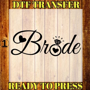 May include: Black "Bride" design with heart accents and a diamond ring illustration. The text "DTF TRANSFER" and "READY TO PRESS" are in yellow. The background is a light wood grain.