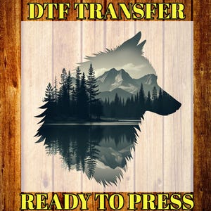 May include: A DTF transfer featuring a wolf silhouette with a landscape design. The design includes a forest, mountains, and a lake, with the text "DTF TRANSFER" and "READY TO PRESS" in yellow.