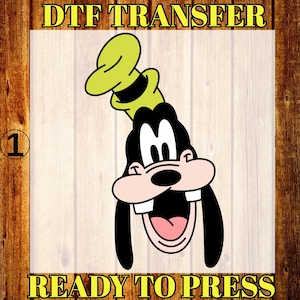 May include: A DTF transfer featuring a cartoon image of Goofy with a green hat and black ears. The image is ready to press and includes the text "DTF TRANSFER" and "READY TO PRESS" in yellow.