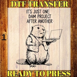 May include: A black and white illustration of a beaver holding a laptop, wearing a vest with a pen in the pocket. The text reads "IT'S JUST ONE DAM PROJECT AFTER ANOTHER" and "READY TO PRESS". The image is a DTF TRANSFER.