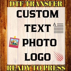 May include: A graphic design featuring the words "DTF TRANSFER" and "READY TO PRESS" in yellow, with the words "CUSTOM TEXT PHOTO LOGO" in black. A small photo is pinned to the design. The background has a wood grain texture.