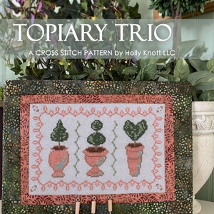 Könnte beinhalten: Ein Kreuzstichmuster für ein Topiary-Trio mit drei Topfpflanzen in verschiedenen Formen. Das Muster ist 7,9 Zoll mal 5,1 Zoll groß und verwendet 28 Count Lugana Stoff. Das Muster ist von Holly Knott Designs.