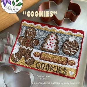 May include: A punch needle pattern for a Christmas-themed embroidery project featuring a gingerbread man, a gingerbread tree, and a gingerbread cookie. The pattern is titled "Cookies" and measures 6 inches by 4 inches.