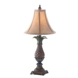 Puede incluir: Una lámpara de mesa decorativa con una base en forma de piña y una pantalla beige. La base es marrón con detalles verdes y la lámpara tiene un diseño clásico. La lámpara mide aproximadamente 71 cm de altura.