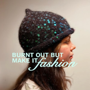 May include: A dark brown knit beanie with teal sequins. The text "BURNT OUT BUT MAKE IT fashion" is overlaid on the image. The beanie has a small, pointed top and a folded brim.
