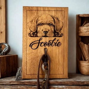 Könnte beinhalten: Haken aus Holz für die Hundeleine mit einem Laser-gravierten Bild eines braunen Welpen, der über den Rand schaut. Der Haken ist mit "Scooby" beschriftet.