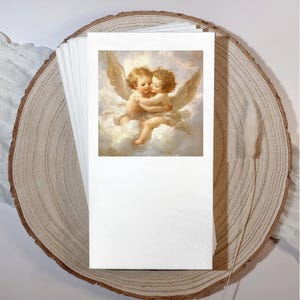 Może przedstawiać: Stos białych papierowych serwetek z nadrukowanym wizerunkiem dw&oacute;ch obejmujących się cherubin&oacute;w na chmurze. Serwetki są prezentowane na plastrze drewna z naturalną krawędzią i suszoną łodygą rośliny.