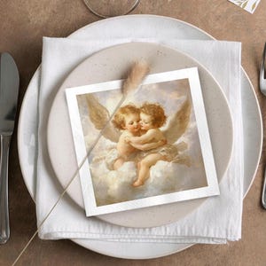 Może przedstawiać: Kwadratowa karta z klasycznym obrazem dw&oacute;ch obejmujących się cherubin&oacute;w, umieszczona na białej serwetce i beżowym talerzu. Cherubiny mają kręcone brązowe włosy i skrzydła na tle chmur. Karta jest częścią ustawienia stołu.