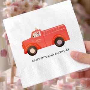 May include: White paper napkin with a red fire truck illustration. The fire truck has black wheels and a ladder on the back. The text "ENGINE NO.1" is on the side of the truck. The text "CAMDEN'S 2ND BIRTHDAY" is printed below the truck.