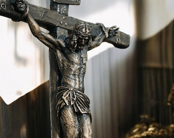 Puede incluir: Escultura de bronce de Jesucristo en la cruz. La figura está detallada con una corona de espinas y un taparrabos. La cruz es de material similar a la madera y la escultura tiene un aspecto envejecido.