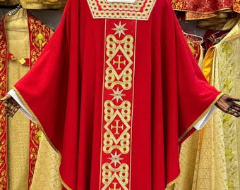 May include: A red liturgical vestment with gold embroidered crosses and starburst designs. The vestment has a square neckline and gold trim. Other liturgical garments are visible in the background.