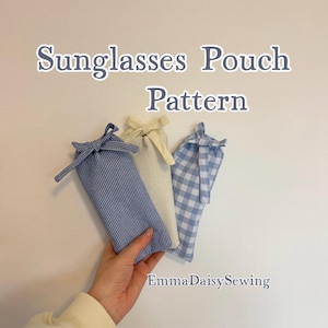 Puede incluir: Tres fundas de tela para gafas de sol con estampados azules y blancos, incluyendo rayas y cuadros, y un color crema liso. Las fundas están atadas en la parte superior con lazos de tela a juego. El texto "Sunglasses Pouch Pattern" se muestra encima de las fundas.