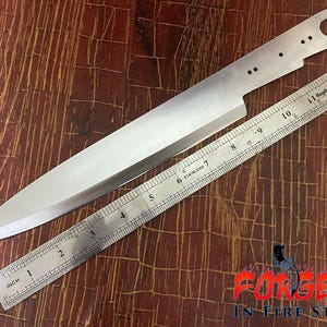 May include: A silver-colored metal knife blade blank with a pointed tip and a handle tang featuring four small holes and one large hole, positioned next to a stainless steel ruler showing a length of approximately 12 inches for the blade.