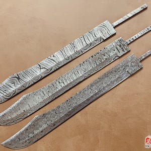 Könnte beinhalten: Drei unterschiedlich große Damastmesserklingen mit einem Muster aus wirbelnden Linien. Die Klingen liegen auf einer braunen Oberfläche. Der Text "FORGED IN FIRE STEEL" ist in der unteren rechten Ecke des Bildes sichtbar.