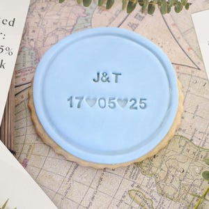 Peut inclure: Un biscuit bleu clair avec les initiales "J&T" et la date "17 05 25" estampill&eacute;es. Le biscuit mesure environ 8,7 cm de diam&egrave;tre. L'image contient &eacute;galement le texte "Offre limit&eacute;e : &Eacute;conomisez 7,5 % sur un lot de 20."