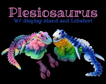 Peut inclure: Sculptures colorées de plésiosaures avec socles et homards. Les sculptures sont dans les tons de rose, bleu, vert et jaune. Le texte "Plesiosaurus W/ display stand and Lobster!" est en haut.